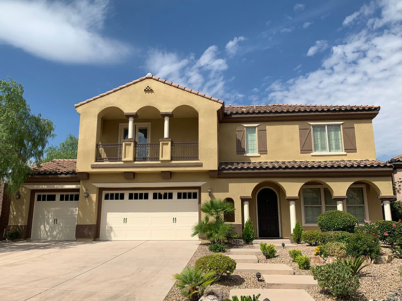 Finished two-storey home with an arched balcony, brown shutters and a tile roof