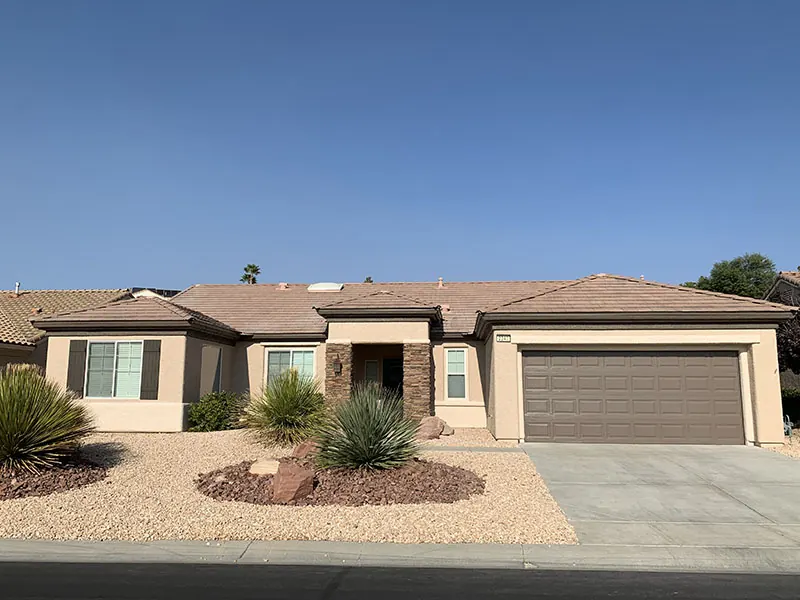 Finished single-storey tan home with a brown garage door and desert landscaping