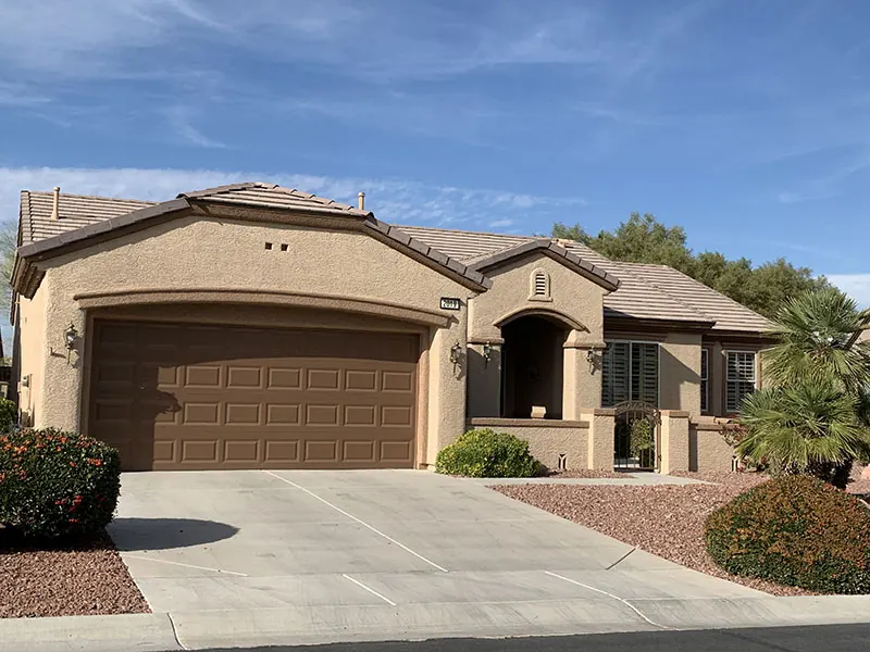 Finished tan home with a wide brown garage door, painted by McMillan & McMillan