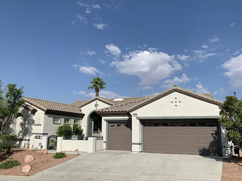 Finished white and grey stucco home with a grey garage door