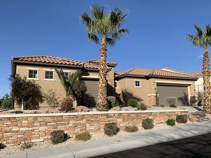 Finished two-tone stucco home with a stacked-stone wall.