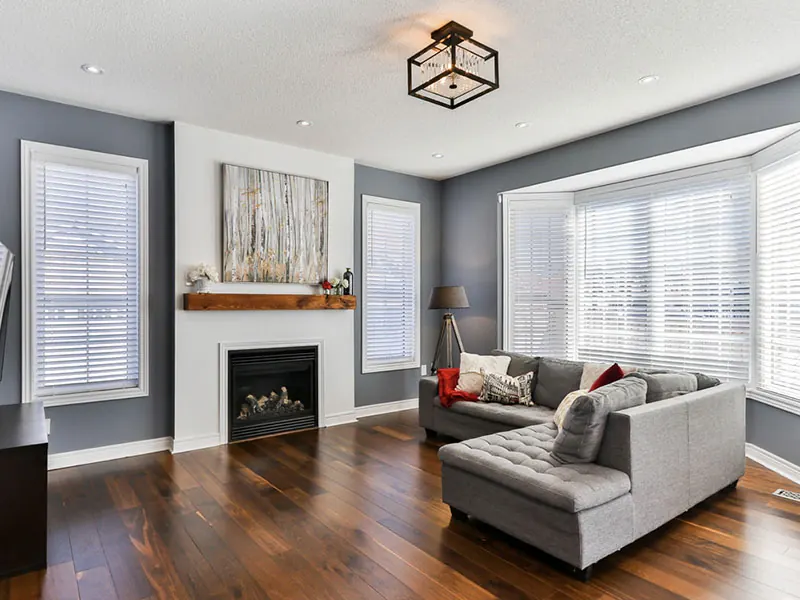 Finished living room with grey-blue walls, white trim and a fireplace