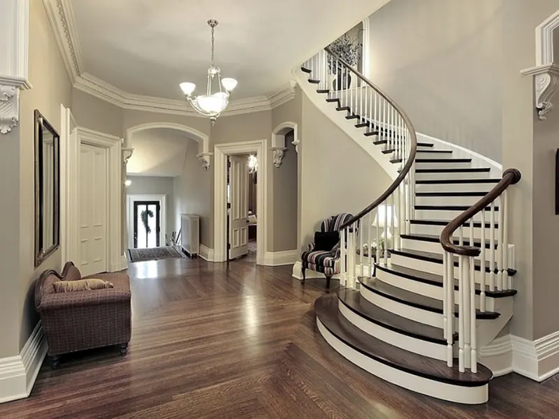 Finished foyer with a curved staircase, cream walls and wood floors